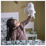 Child holds soft owl puppet in cozy room