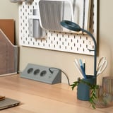 Modern desk setup with SKOTAT extension cord, multi-outlet & usb, and blue gooseneck lamp.