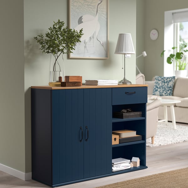 Blue sideboard with plant, books, wall poster.