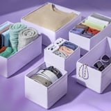 Organized boxes hold socks, belts, and accessories. Different sizes keep items neat. Recycled material, stacks in drawers.