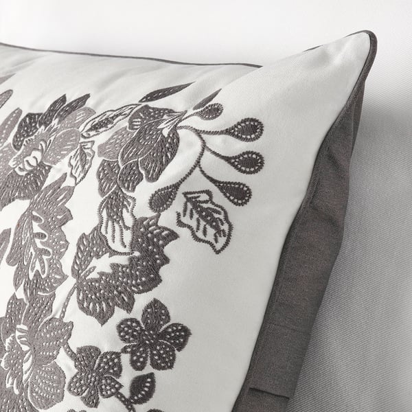 Embroidered floral cushion with zipper closure. Gray tones, cotton exterior, recycled polyester filling.