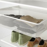 White mesh storage drawer holding folded clothes, part of an organizational system in a closet.