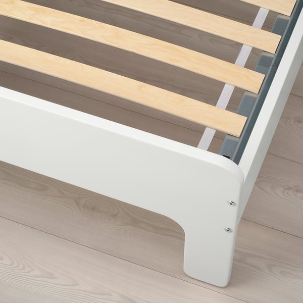 Close-up of bed frames corner shows metal and wooden slats, illustrating sturdy support.