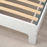 Close-up of bed frames corner shows metal and wooden slats, illustrating sturdy support.