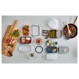 Top view of wooden cutting board, various food items, and colorful plastic containers of different sizes.