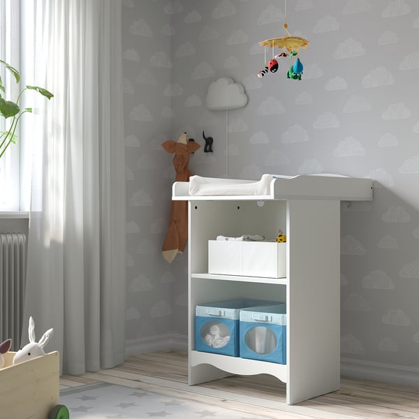 White SMÅGÖRA changing table in nursery with blue boxes, cloud wallpaper, mobile, and stuffed animals.