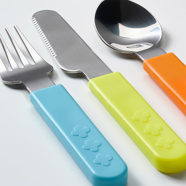 Three kids utensils: fork, knife, spoon with colorful handles. Handles are blue, green, orange. Knife serrated. All metallic.