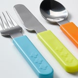 Three kids utensils: fork, knife, spoon with colorful handles. Handles are blue, green, orange. Knife serrated. All metallic.