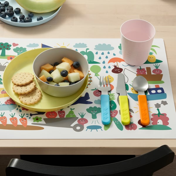 Colorful childrens cutlery and plate on a playful mat. Includes a knife with a serrated edge for easy cutting.