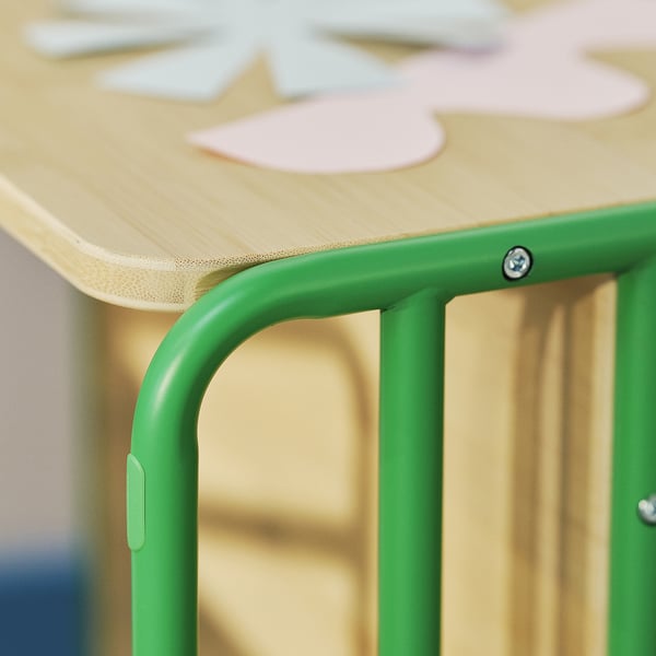 A green kids table with a curved design. The tabletop is made of bamboo, supported by a green metal frame.