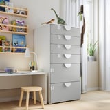 Kids room with gray SMÅSTAD chest, wooden shelves full of colorful books, a small desk with a lamp and stool, and dinosaur toys on the dresser.