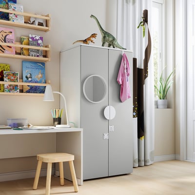 Kids room with light gray SMÅSTAD wardrobe, dinosaur toys, wooden stool, bookshelf with colorful books.
