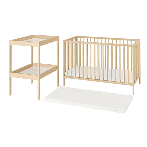 A light-colored wooden baby furniture set including a cot, changing table, and mattress.