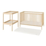 A light-colored wooden baby furniture set including a cot, changing table, and mattress.