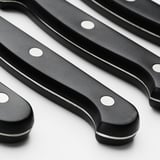 Four steak knives with black handles and serrated blades.