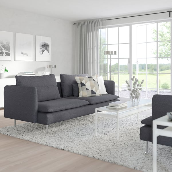 Modern living room with SÖDERHAMN sofa, coffee table, and windows showing greenery. Minimalist design.