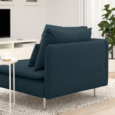 Blue sofa with square cushions on thin metal legs in cozy living area with side table and cup.