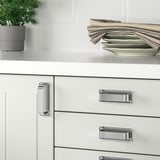 White kitchen cabinets with chrome SÖRBYN handles, stack of plates and towels on countertop.