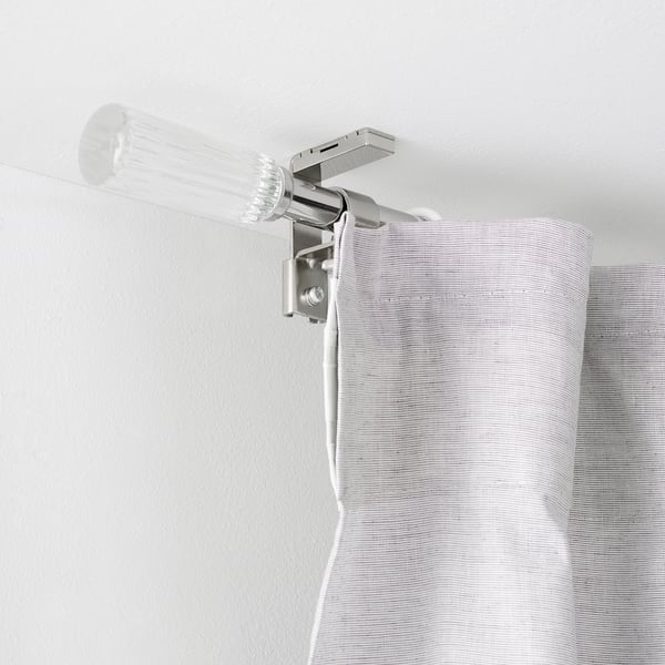 Clear curtain rod mounted near ceiling with white cord dangling, likely for automated curtain control.