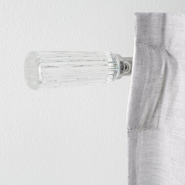 Modern wall-mounted curtain rod, polished chrome and clear glass finials, sleek design.