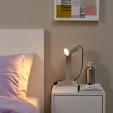 Modern bedroom with SOLHETTA lamp, yellow pillows, books, and abstract painting.