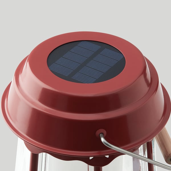 Red solar-powered lamp with glass top, sturdy metal stand, and solar panel for eco-friendly lighting.