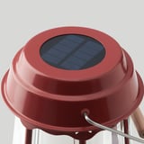Red solar-powered lamp with glass top, sturdy metal stand, and solar panel for eco-friendly lighting.