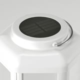 Sleek, modern solar lamp with clean lines. White body, stainless steel handle, and protective glass top. Emits warm decorative light.