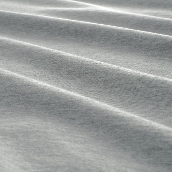 Soft, textured bed sheet. Crinkled, light grey fabric, slightly wrinkled, giving a cozy feel.
