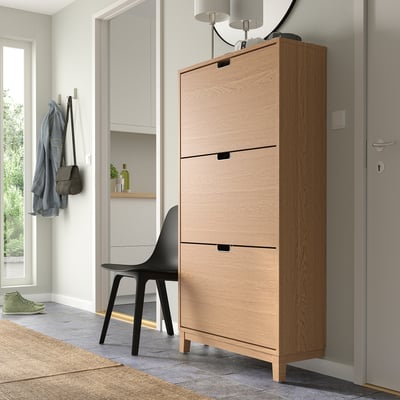 Wooden STÄLL shoe cabinet in light oak, 3 compartments. Black chair for size reference.