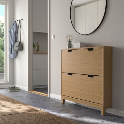 Wooden STÄLL shoe cabinet in hallway with mirror & decor, near coat rack and grey unit.
