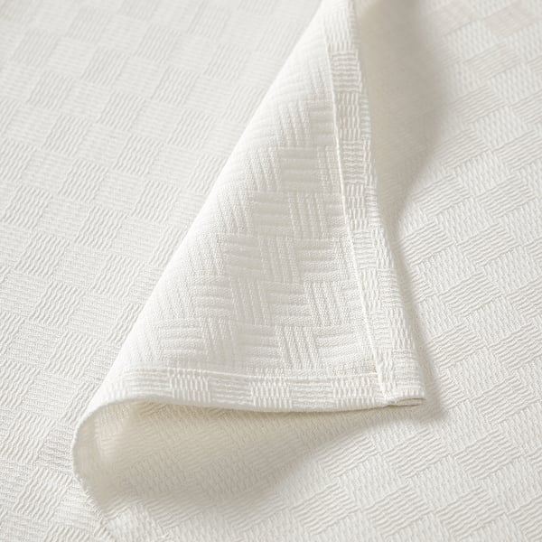 White bedspread with intricate weave pattern, folded neatly, showcasing soft, high-quality cotton texture.