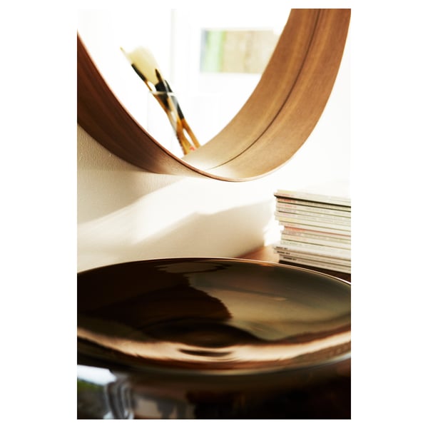 Curved wooden-framed mirror with a sleek design. A small shelf at the bottom, perfect for small items. Reflective glass shows clear reflections.