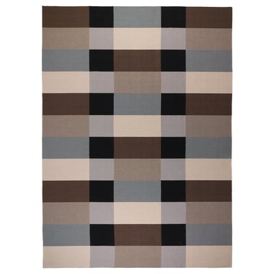 A brown, multicolored checkered rug named STOCKHOLM, handwoven in wool, featuring a bold pattern and rectangular shape.