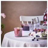 Red candle, fruit plate on table, glasses, bottle.