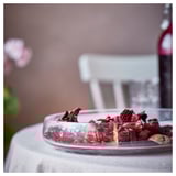 A bowl of red, dried plant potpourri on a white tablecloth.