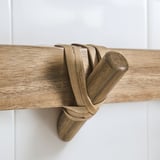 Wooden robe hook, part of the STOREDAMM series, crafted from acacia with clear lacquer finish, mounted on a white wall.