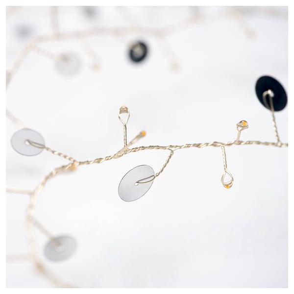 Elegant string light with silver discs, emitting warm glow.