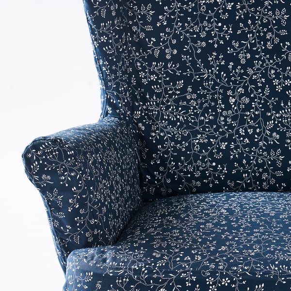 A wingback chair with dark blue patterned fabric featuring white floral designs, showcasing high-quality material and craftsmanship.