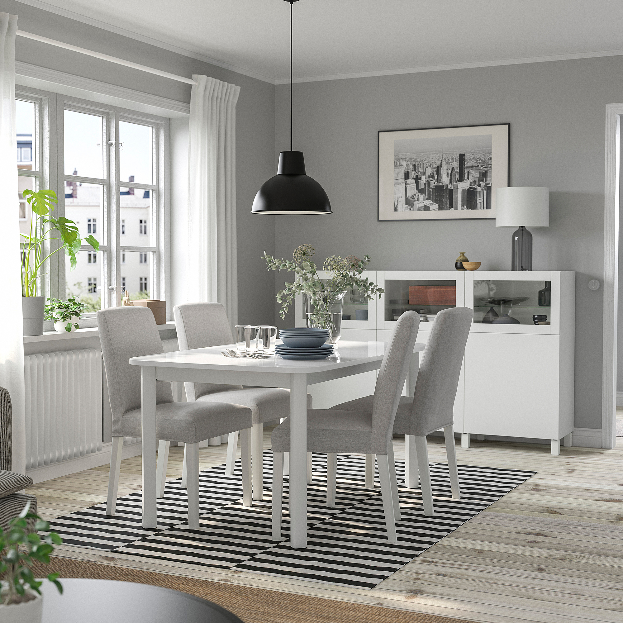 STRANDTORP white extendable dining table with gray chairs, stripe rug, black pendant light, framed city print, large window, soft lighting.