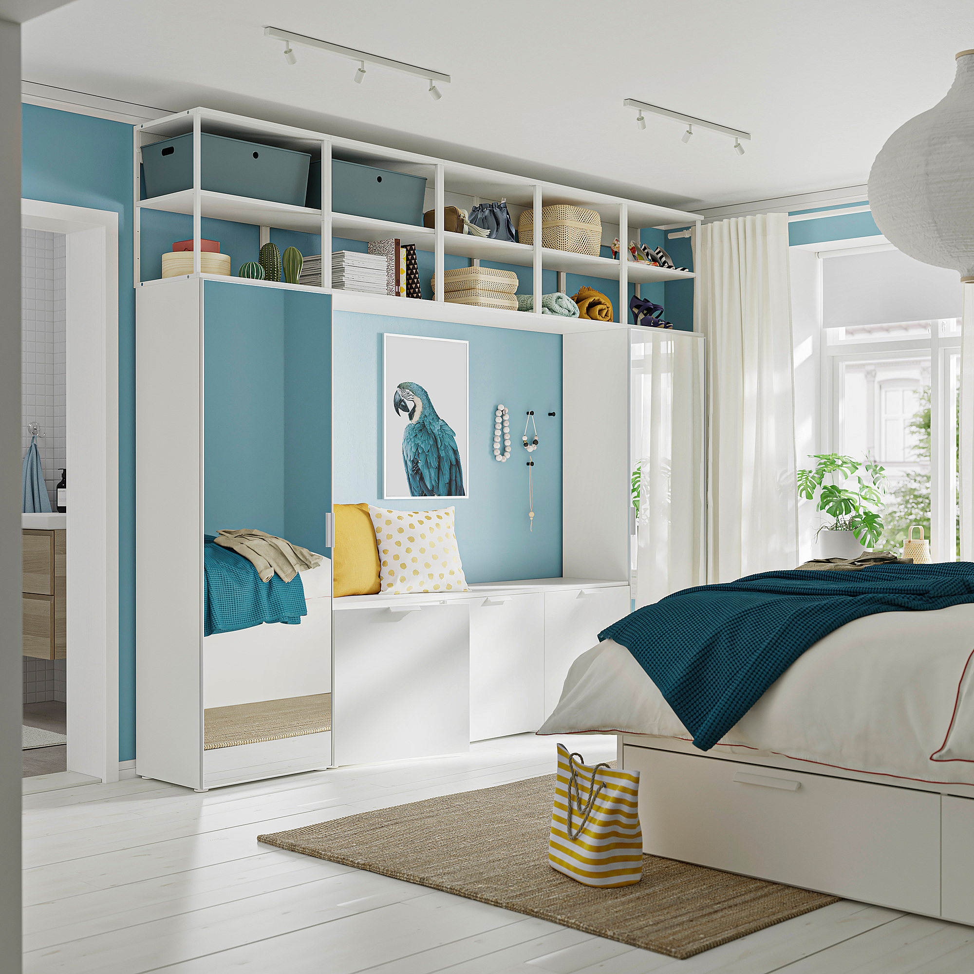 Bright bedroom with white STRAUMEN mirror doors, blue accents, and a parrot artwork.