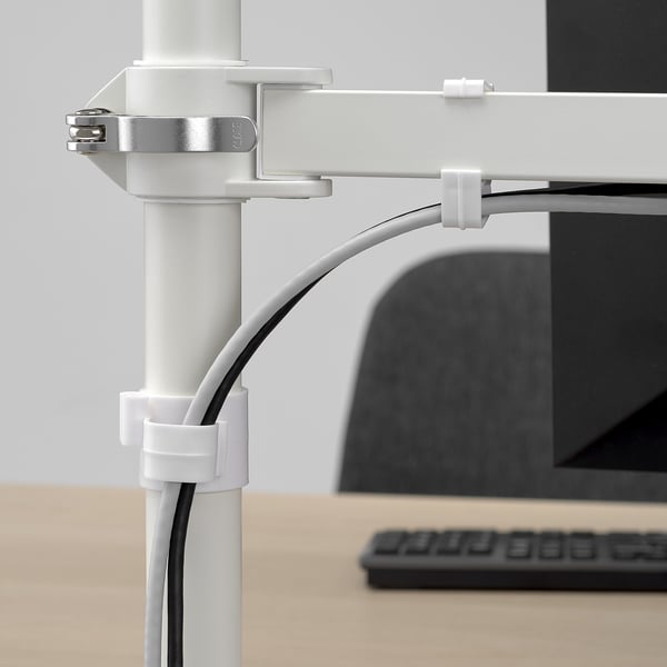 Adjustable monitor arm mounted on table with white STUBBERGET clamps, cables neatly organized.