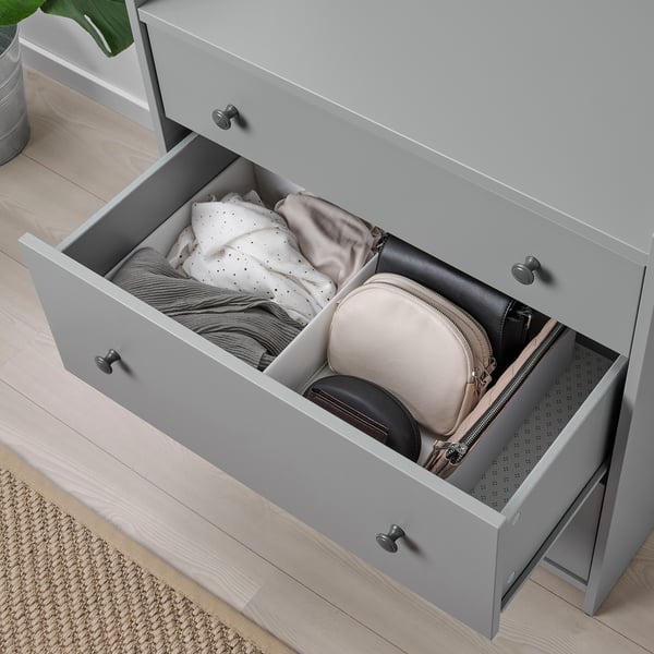 Two grey drawers open, showing folded clothes and purses. Organized with STUK boxes.