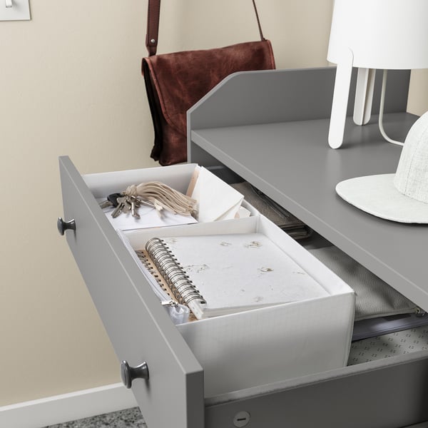 Gray drawer organizer on a dresser, holding keys, notebook, and other small items, with a matching gray tray.