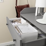 Gray drawer organizer on a dresser, holding keys, notebook, and other small items, with a matching gray tray.