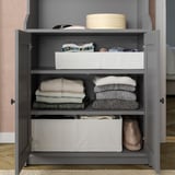 Open gray STUK cabinet showing neatly folded clothes in white boxes, socks, and accessories.