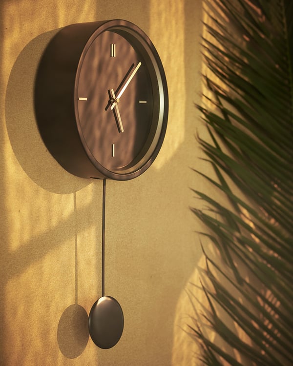 A modern round wall clock named STURSK in bronze color. Made of metal and glass, it minimalist design with a swinging pendulum.