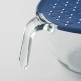 Close-up of clear glass bowl with blue plastic lid, showing quality and design.