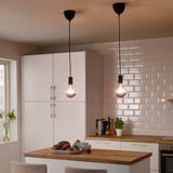 Two SUNNEBY pendant lights over kitchen island with fruit, plates, and plant.