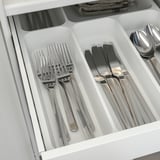 Silverware organizer with forks, knives, and spoons in compartments.
